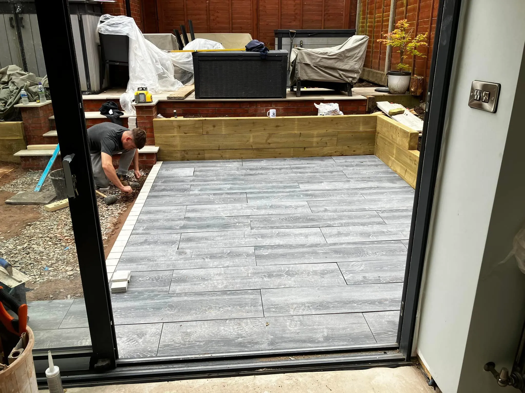 A man working on a patio in a backyard.