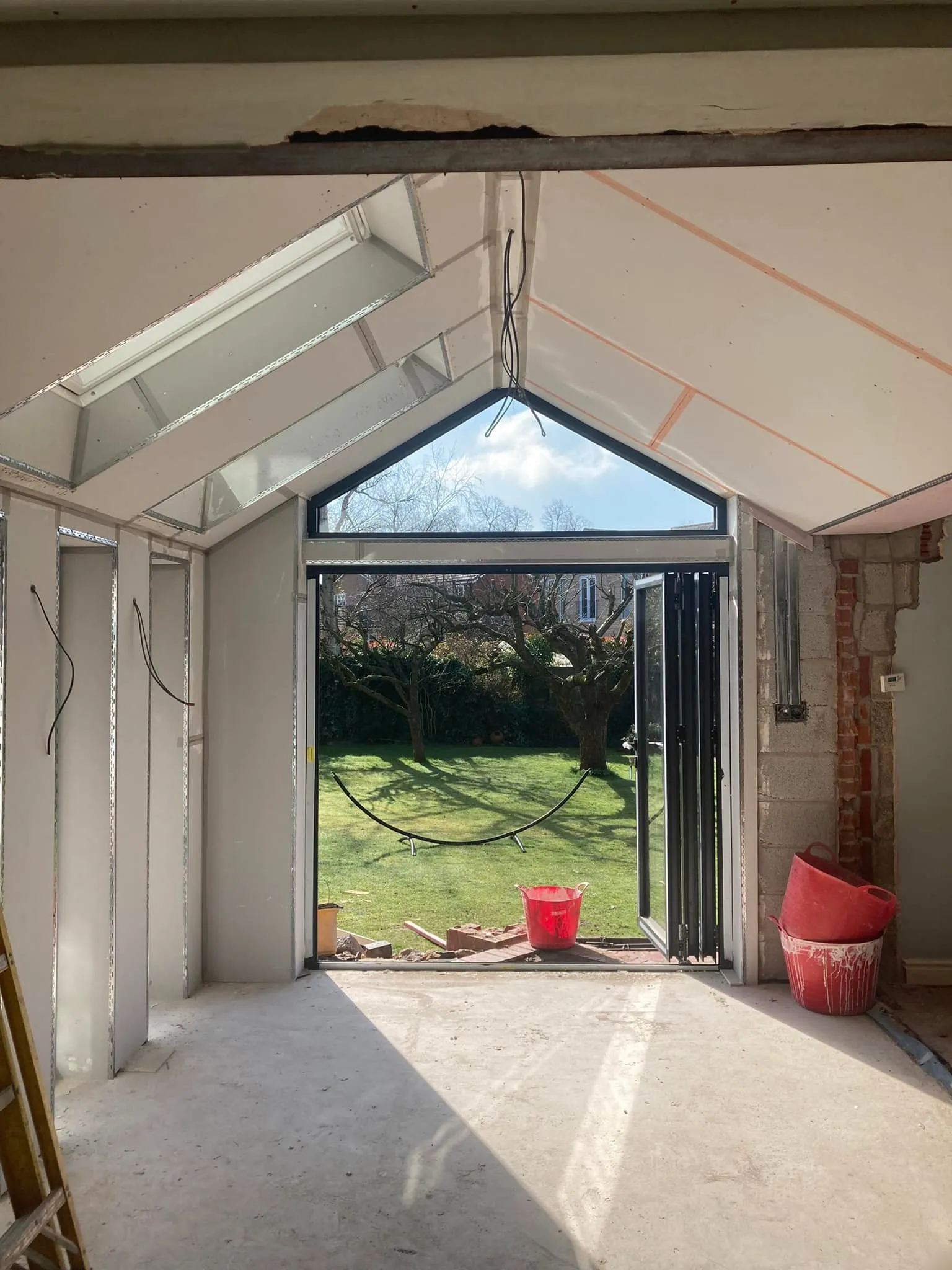 A room with a glass door and a red bucket.
