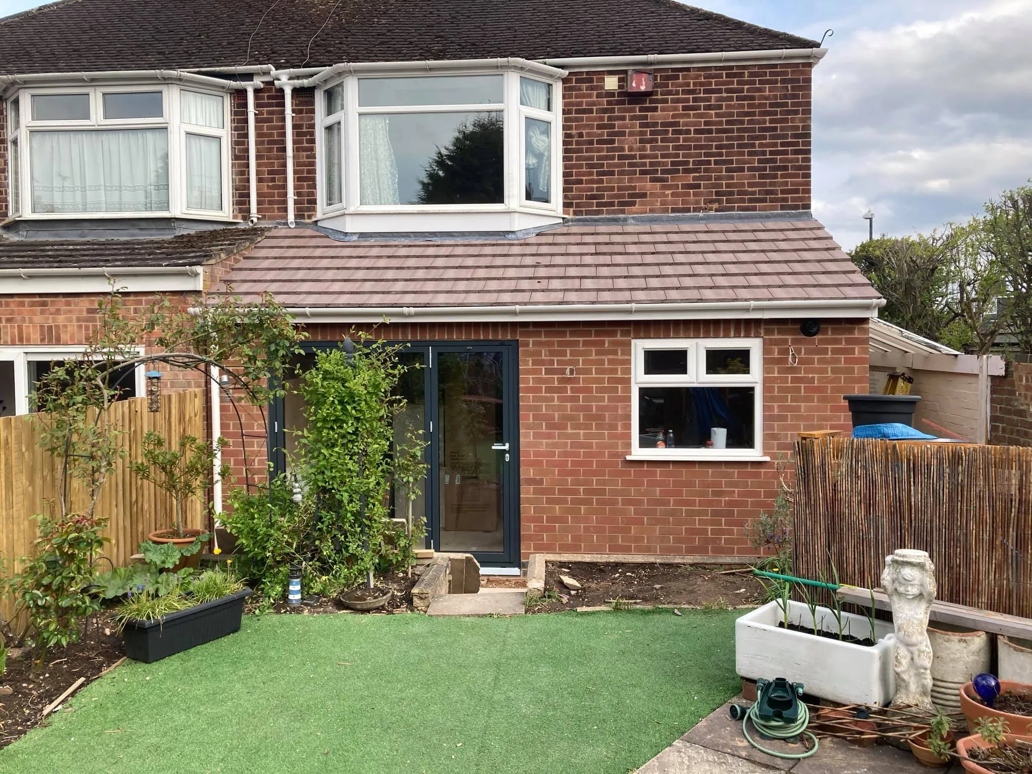 A brick house with a green lawn in front of it.