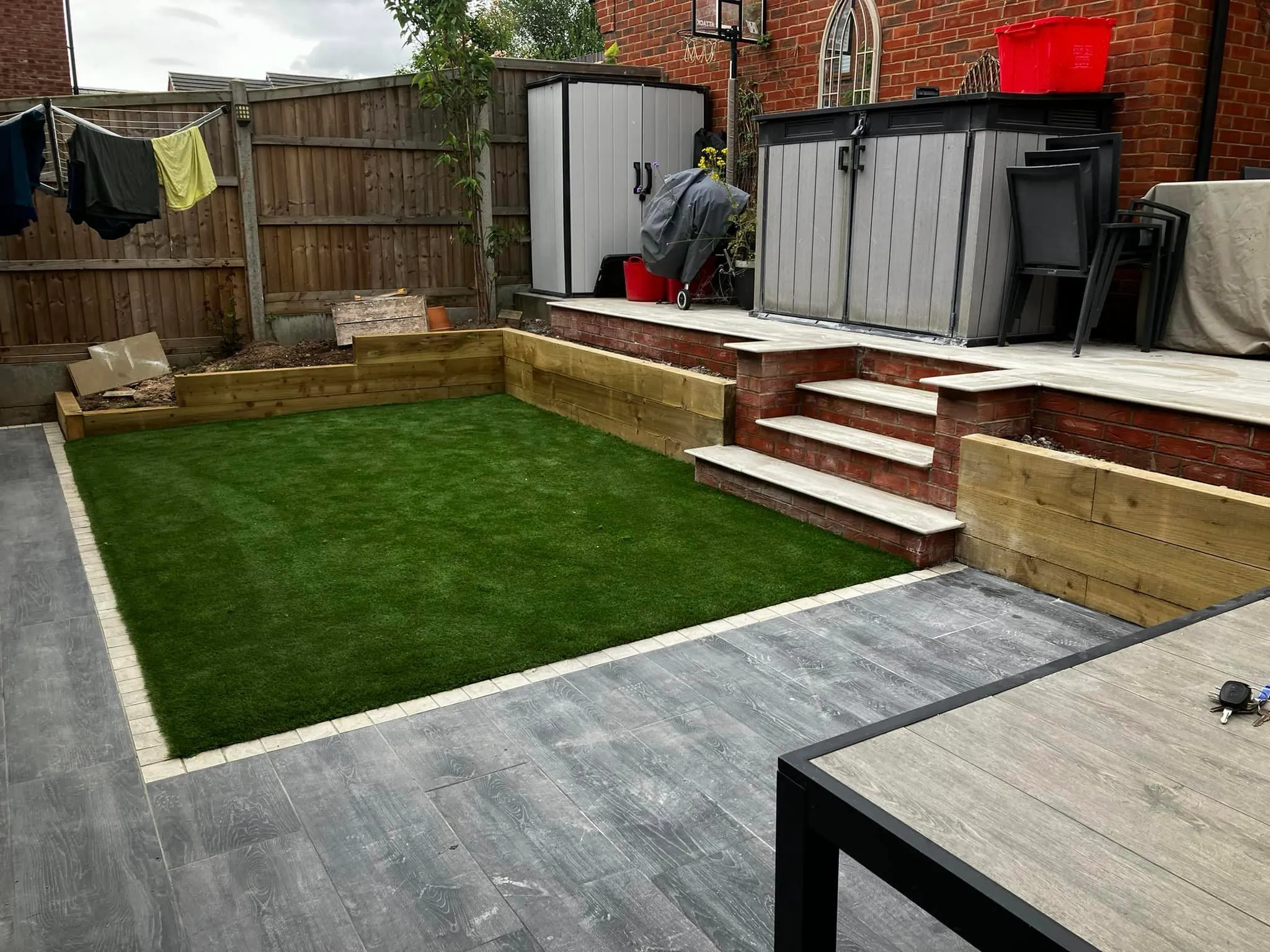 A small backyard with a grass lawn and wooden steps.