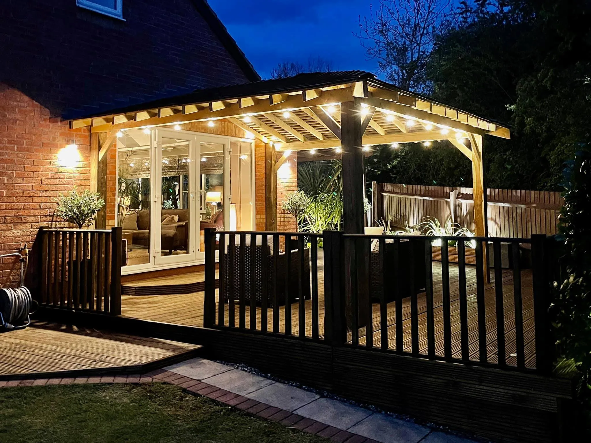 A deck with a gazebo lit up at night.